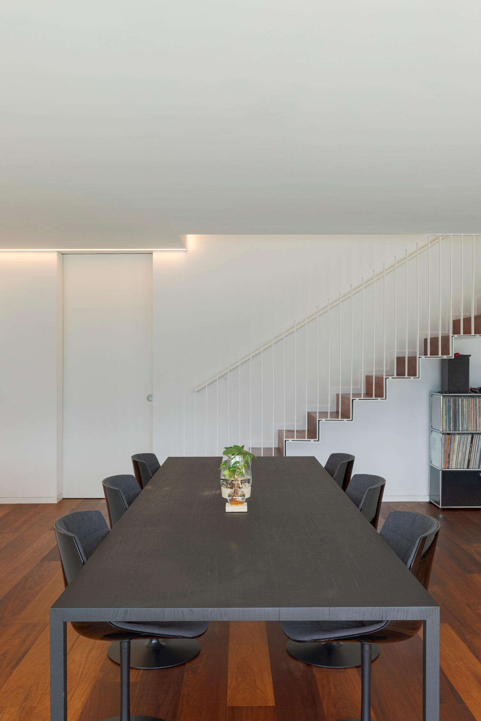 Minimal dining room with dark wood table and floating staircase